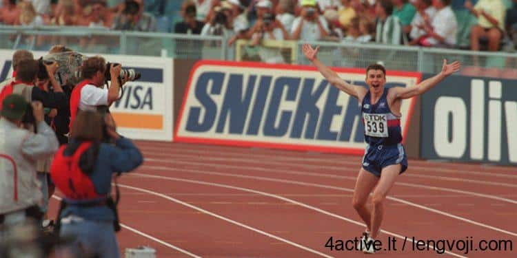 edwards_in-750x375 - 4Active Sprinter in blue raises arms in victory as photographers line the track’s left side and spectators cheer in the background.