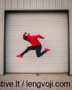 larry-george-ii-ATnd89IcOT0-unsplash - 4Active - 4Active Person in a red hoodie and red sneakers jumps mid-air in front of a large white roll-up garage door.