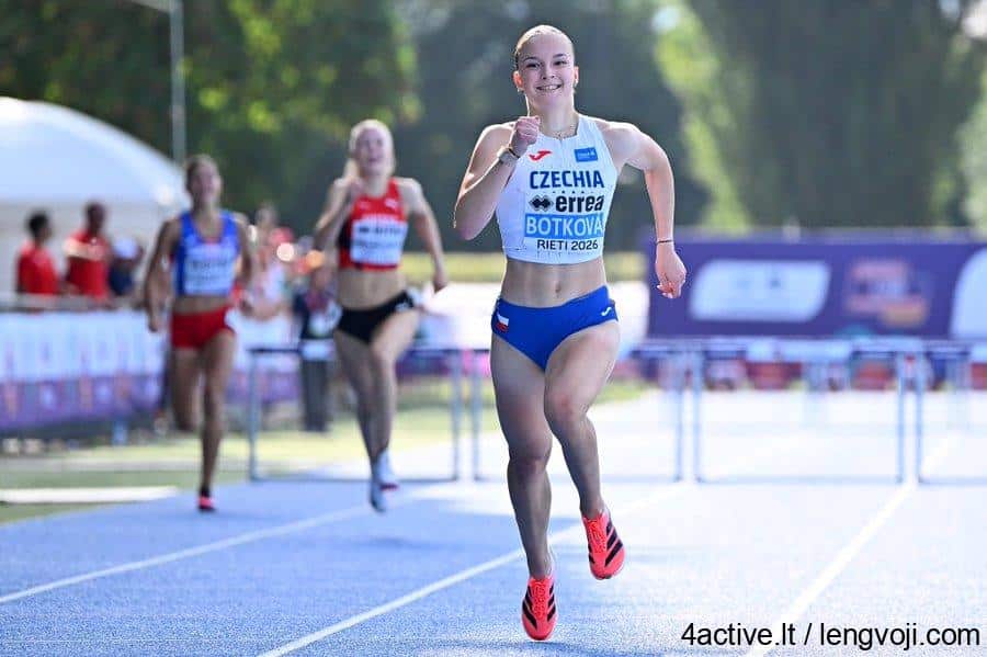 Botkova - 4Active Young female sprinter in blue Czechia kit finishing a race on a blue track, giving a thumbs-up with a smile. Behind her, other runners and spectators blur in the background.