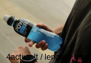 Energetiniai gerimai - 4Active - 4Active A person holding a blue Powerade sports drink bottle outdoors, with a smartwatch visible on their wrist.