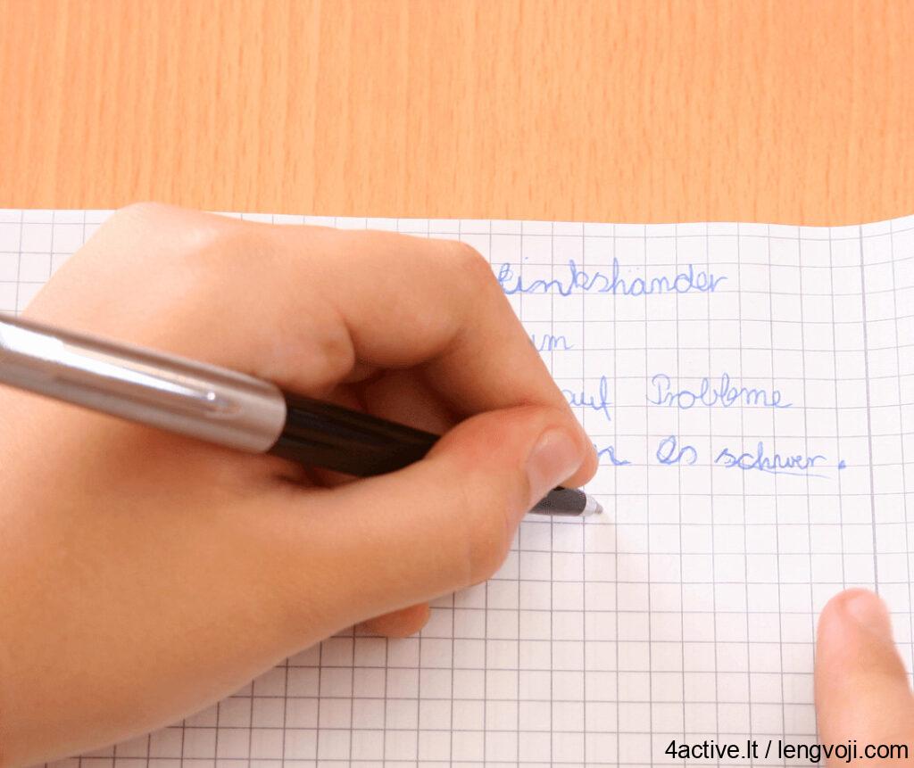 Close-up of a hand writing with a black pen on graph paper