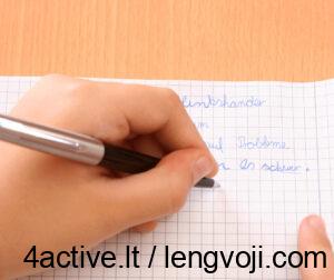 Close-up of a hand writing with a black pen on graph paper