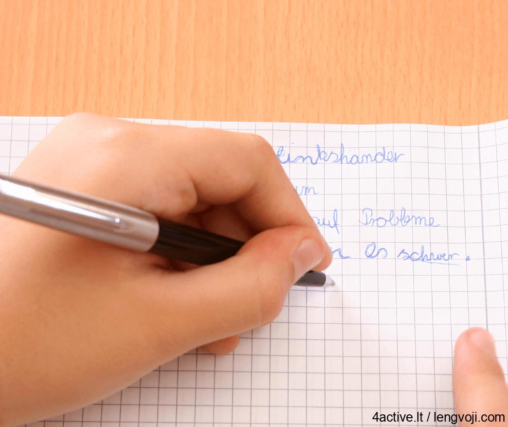 Close-up of a hand writing with a black pen on graph paper