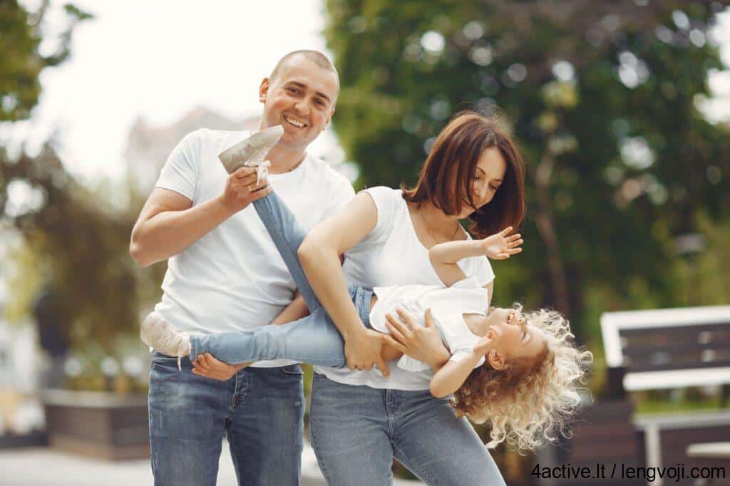 woman in white tank top and blue denim jeans carrying girl in white dress